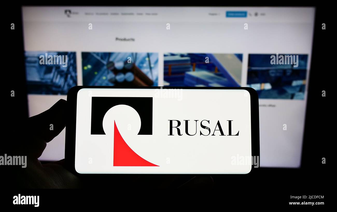 Person, die das Smartphone mit dem Logo der russischen Firma United Company RUSAL IPJSC auf dem Bildschirm vor der Website hält. Konzentrieren Sie sich auf die Telefonanzeige. Stockfoto