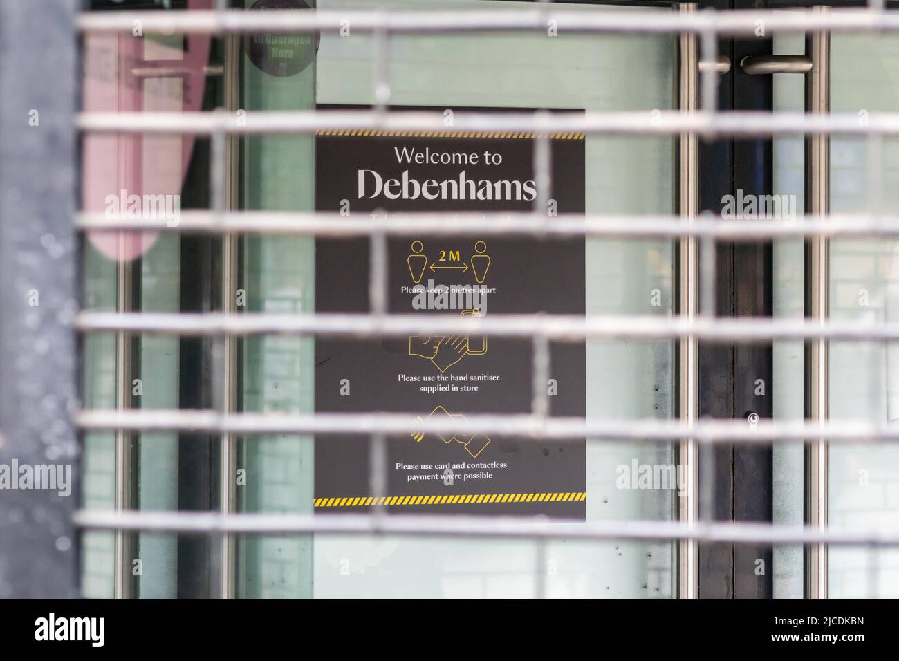 Willkommen in Debenhams, unterschreiben Sie mit den COVID-19-Richtlinien, die durch geschlossene Fensterläden im Geschäft in der Manchester Market Street gesehen werden. „Tod der Hauptstraße“. VEREINIGTES KÖNIGREICH Stockfoto