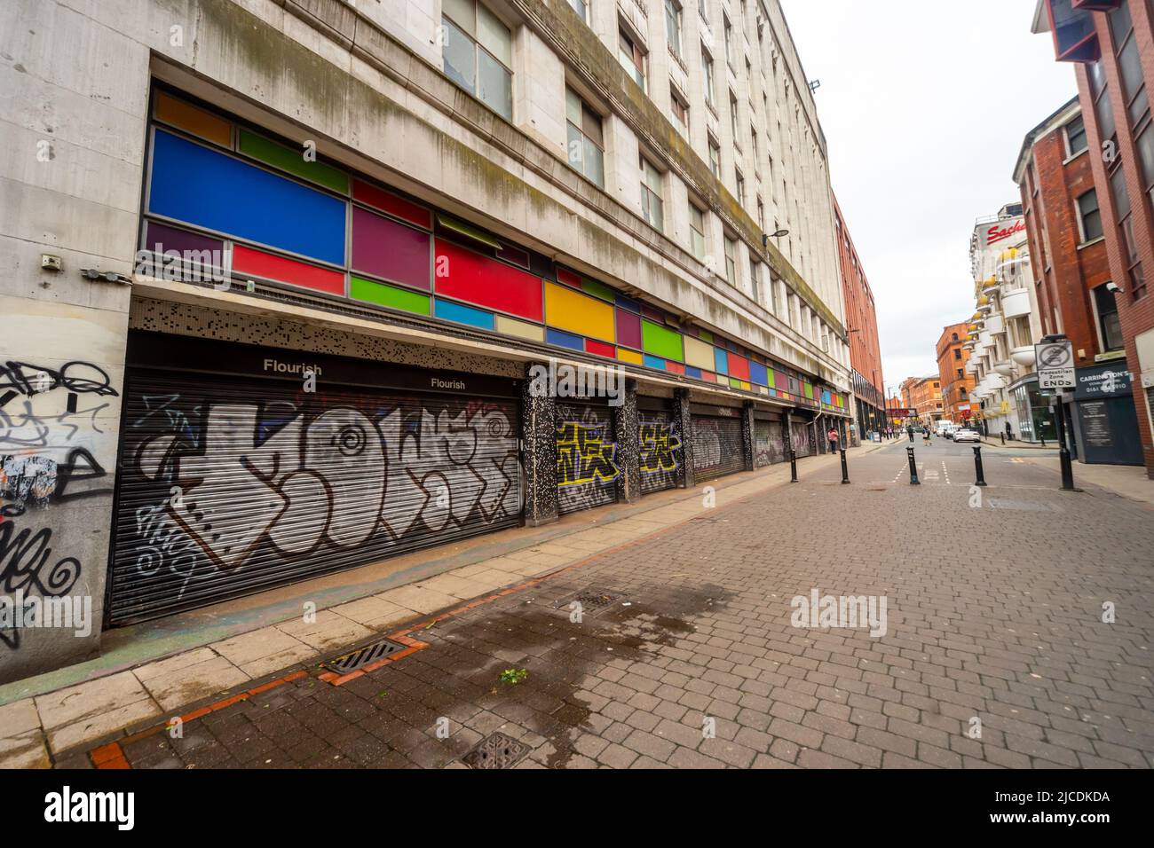 Sprühen Sie Graffiti und leuchtende Farben auf die geschlossenen Fenster eines Gebäudes in der TIB Street, Manchester, England, Großbritannien Stockfoto