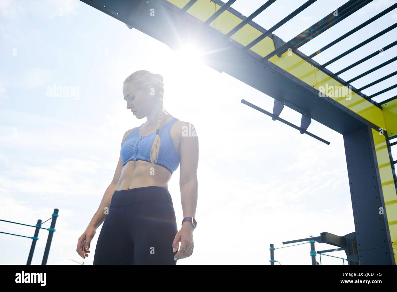 Serious schöne junge blonde Frau mit perfekten Körperformen stehen am Trainingsbereich im Sonnenlicht Stockfoto