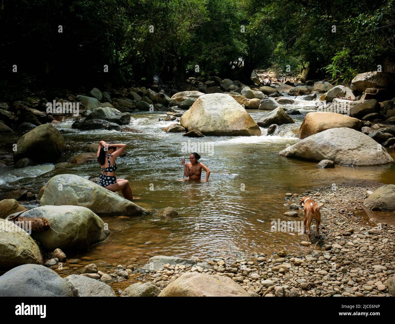 Cisneros, Antioquia, Kolumbien - 20. Februar 2022: Zwei Freundinnen am Fluss, die sich mitten in der Natur gegenseitig Bilder machen Stockfoto