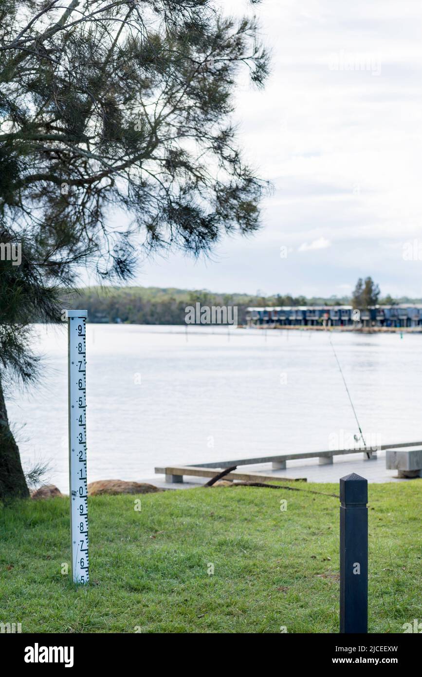 Ein Tiefenmarker in der Nähe von Ferienhütten, die am Ufer des Lake Conjola an der australischen Südküste, NSW, gebaut wurden Stockfoto