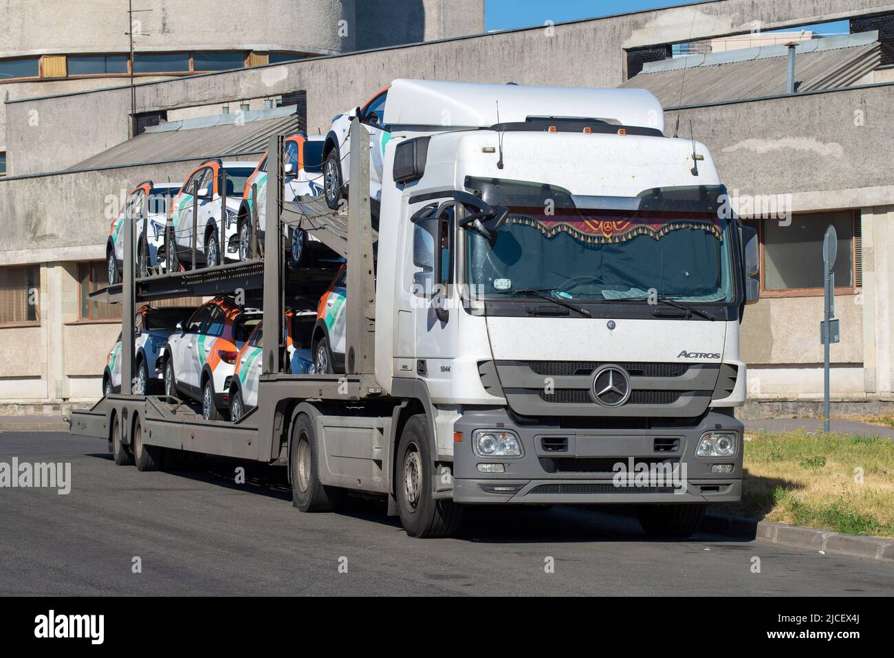 SANKT PETERSBURG, RUSSLAND - 17. JULI 2021: Autotransporter 'Mercedes Benz' mit neuen Autos der Carsharing-Firma 'Delimobil' wartet auf Entladung Stockfoto