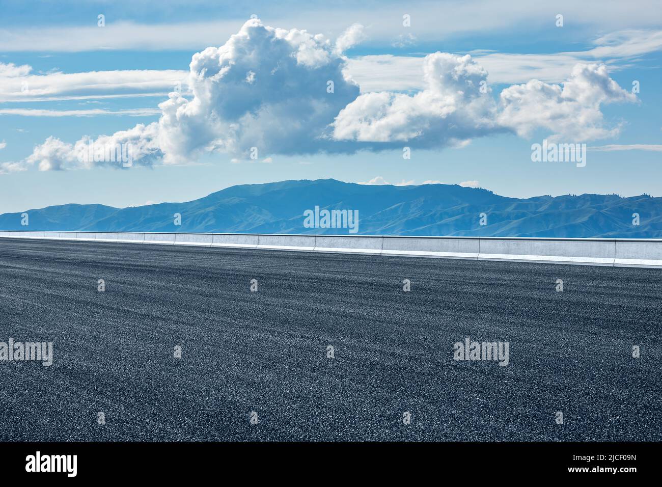 Asphaltstraße und Berglandschaft unter blauem Himmel Stockfoto