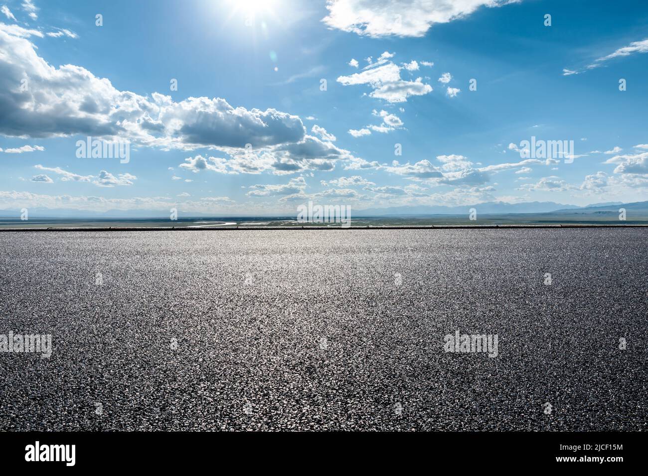 Asphaltierte Straße und wunderschöne Himmelswolkenlandschaft unter blauem Himmel Stockfoto
