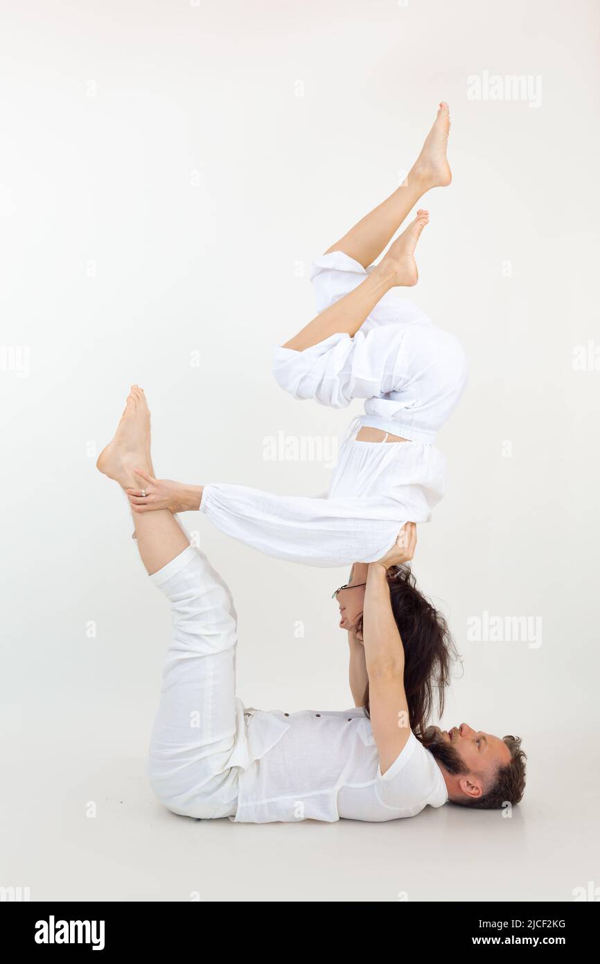 Vertikale Studioaufnahme von Mann und Frau, Familie bei Sportübungen, Fitness und Yoga. AcroYoga-Lehrer im Studio Stockfoto
