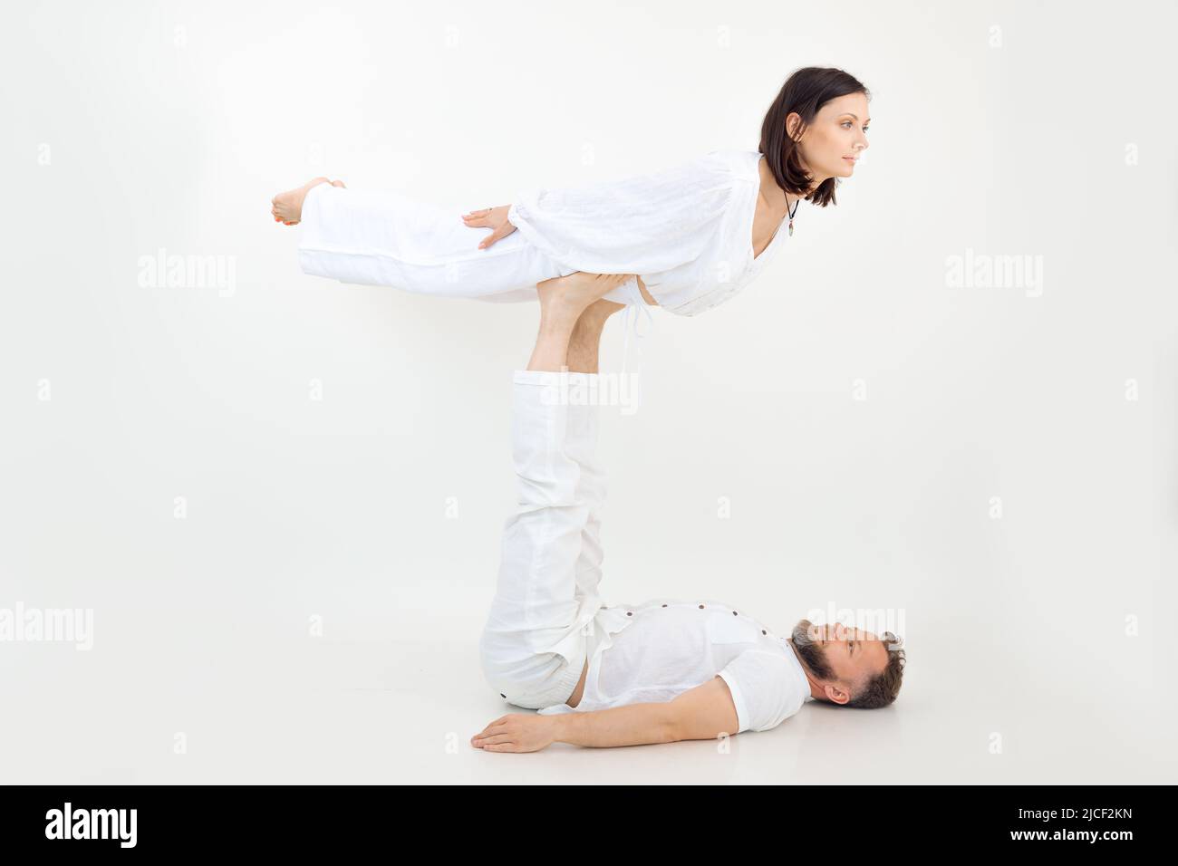 Mann und Frau, Paar bei Sportübungen, Fitness und Yoga. Mann, der das Weibchen auf den Beinen hält, Haltungen übt, Vertrauen Stockfoto