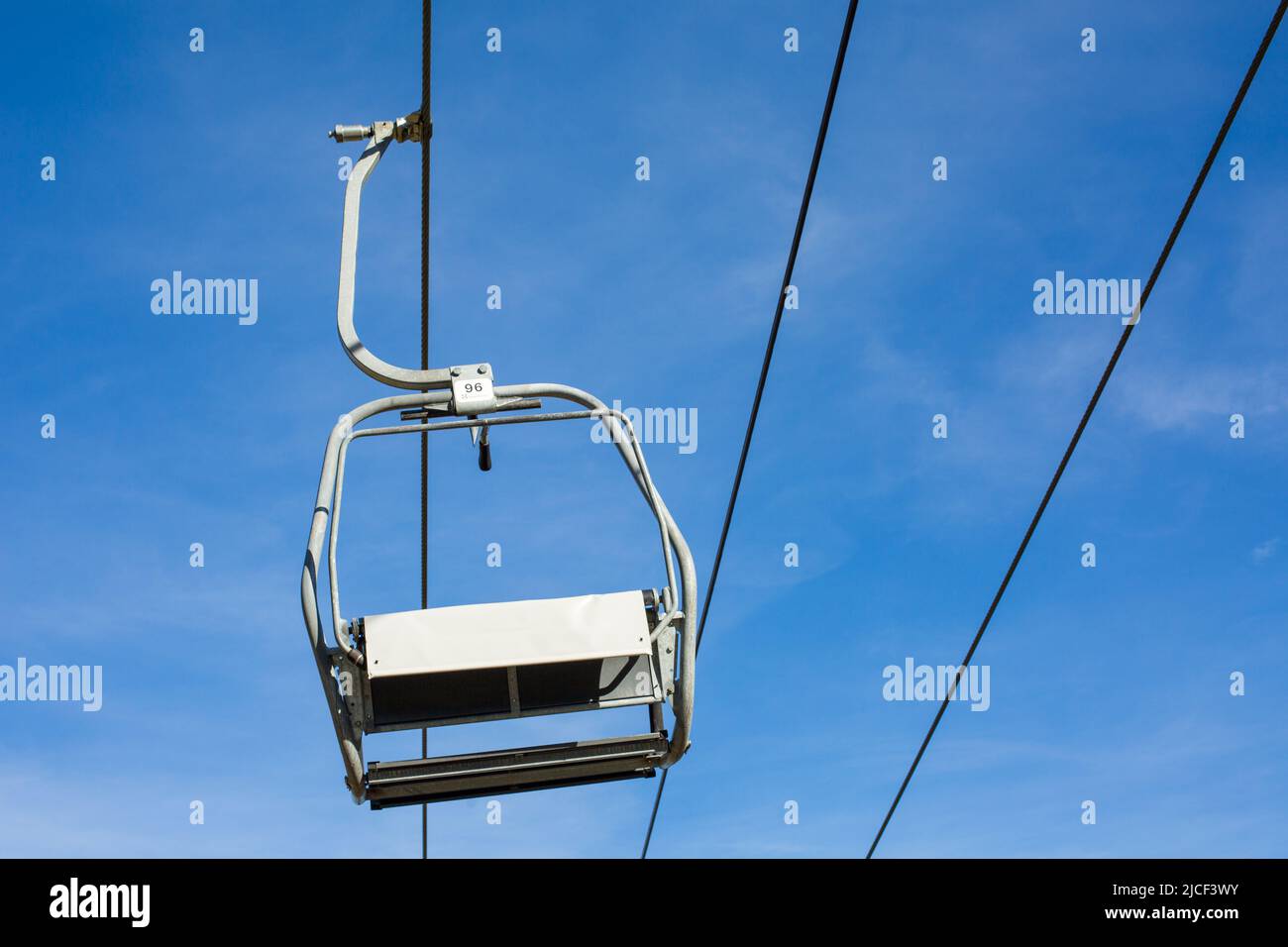 Oberammergau, Deutschland - 31. Okt 2021: Blick auf einen einzelnen, hängenden Sessellift. Blauer Himmel im Hintergrund, keine Menschen. Stockfoto