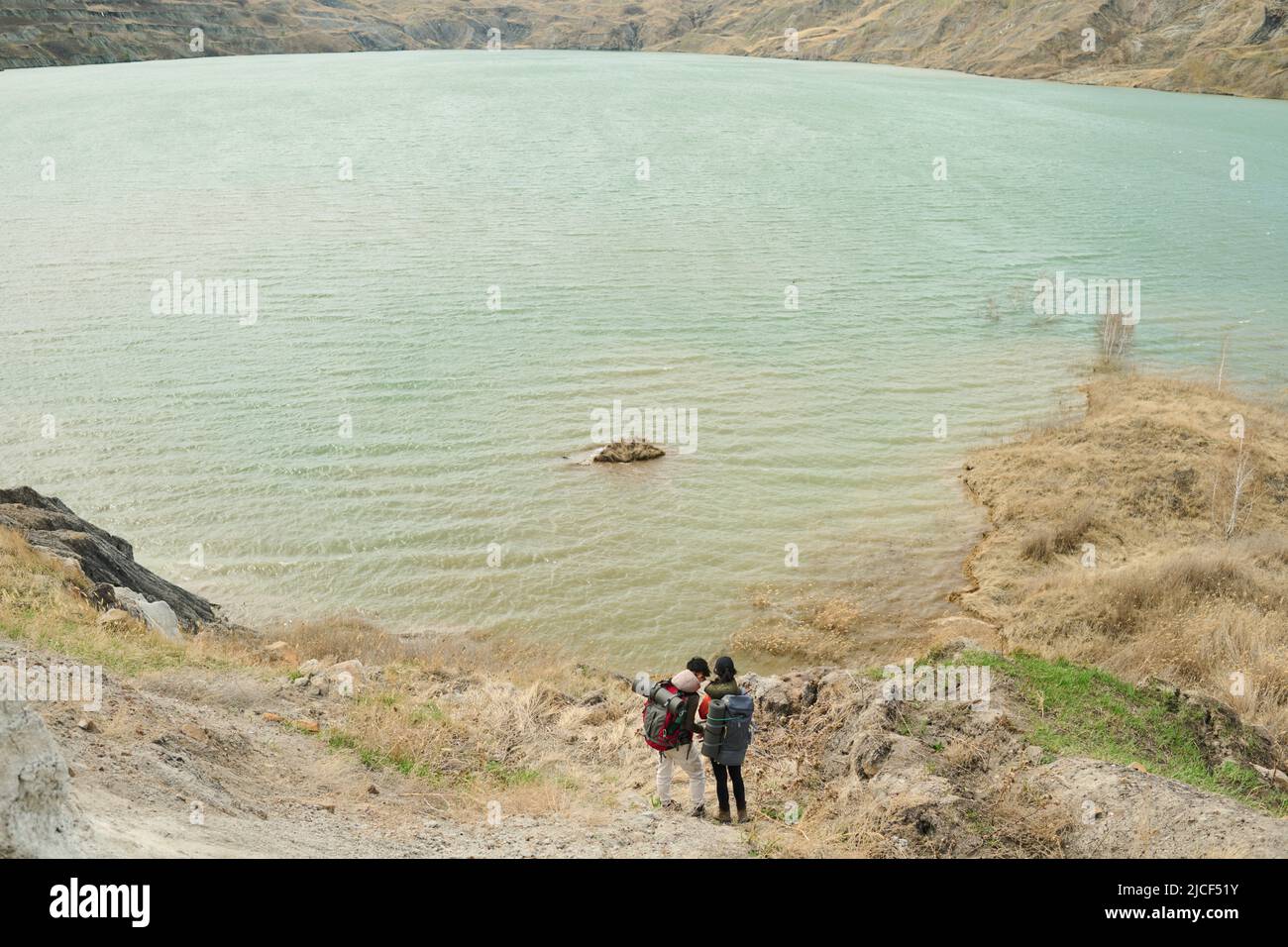 Extrem lange Aufnahme von zwei nicht erkennbaren weiblichen Touristen in Rucksäcken, die am malerischen Ufer des Steinbruchs stehen Stockfoto