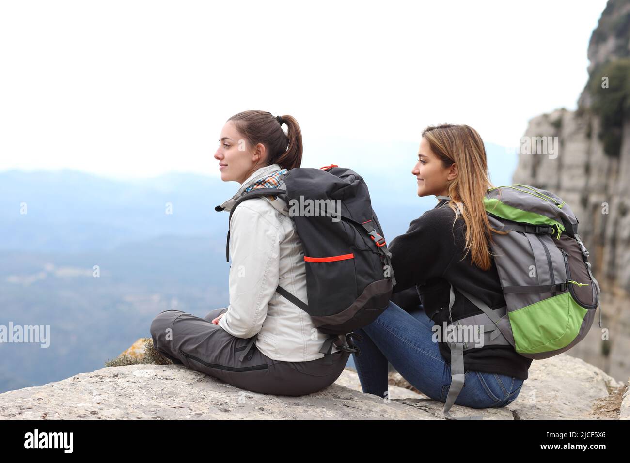 Zwei Rucksacktouristen betrachten die Aussicht auf einer Klippe in den Bergen Stockfoto