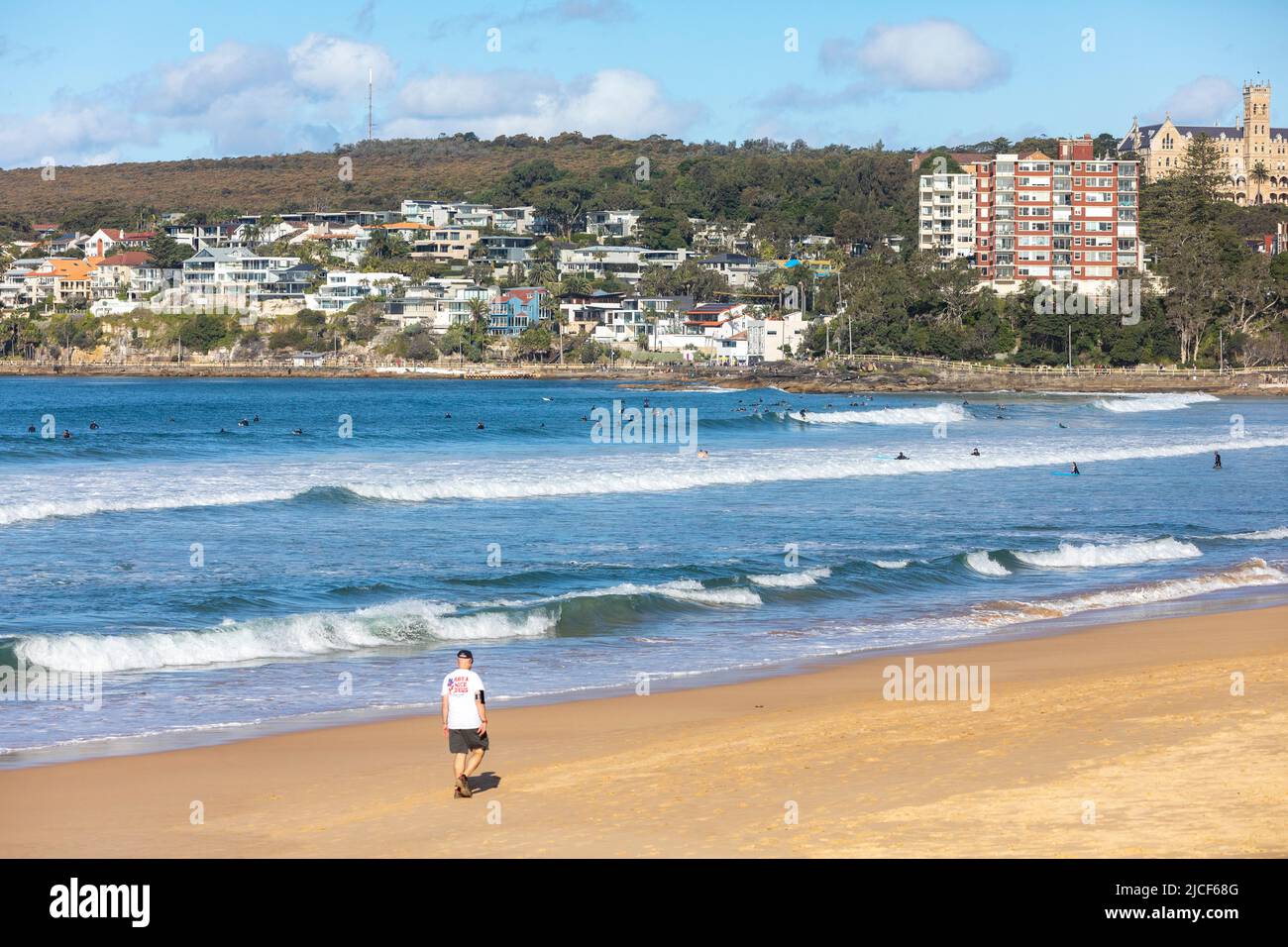 Manly Beach Sydney, Mann mittleren Alters trainiert am Strand, Surfer im Meer, blauer Himmel am Wintertag, Sydney, NSW, Australien Stockfoto