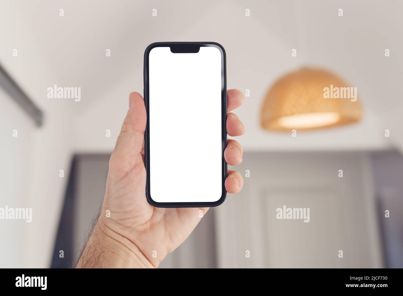 Smartphone-Mockup, Internet der Dinge und Smart-Home-Konzept, Mann mit Mobiltelefon. Nahaufnahme der Handhaltevorrichtung mit leerem Bildschirm im Home Interi Stockfoto