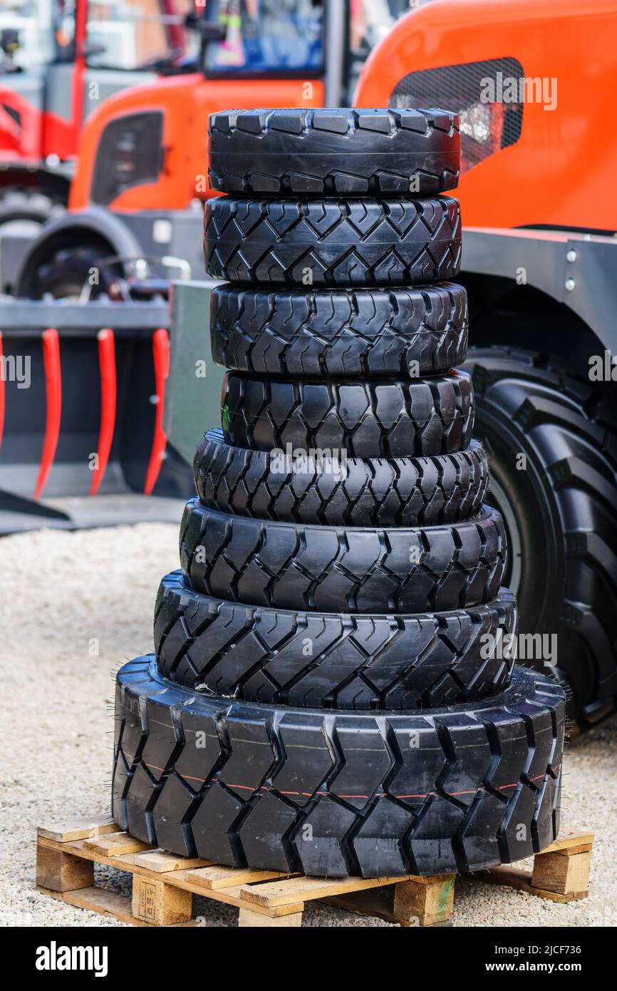 Gestapelte landwirtschaftliche Traktorreifen mit Maschinen im Hintergrund, selektiver Fokus Stockfoto