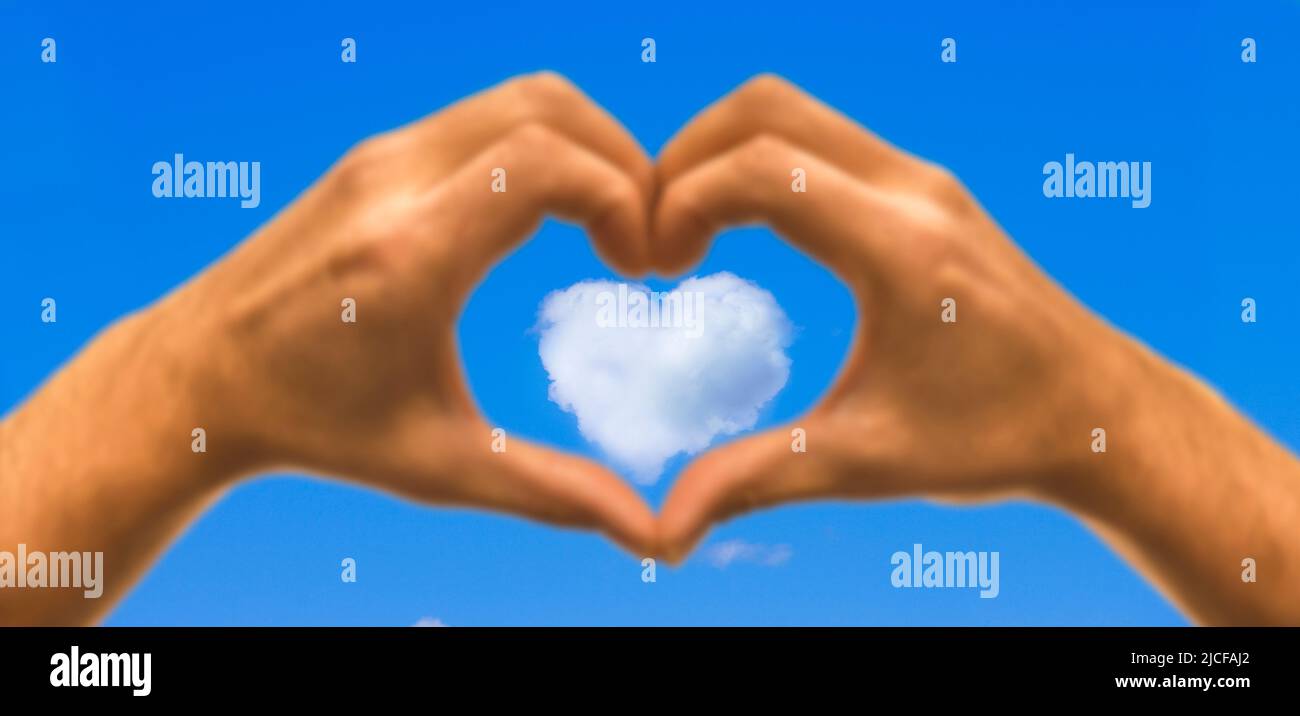 Hand Herz vor blauem Himmel mit Wolkenherz Stockfoto