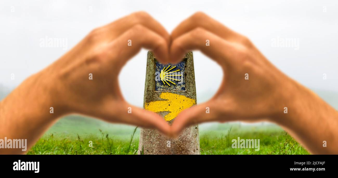 Hand Herz vor einem Wegweiser mit Pilgermuschel auf dem Jakobsweg Stockfoto