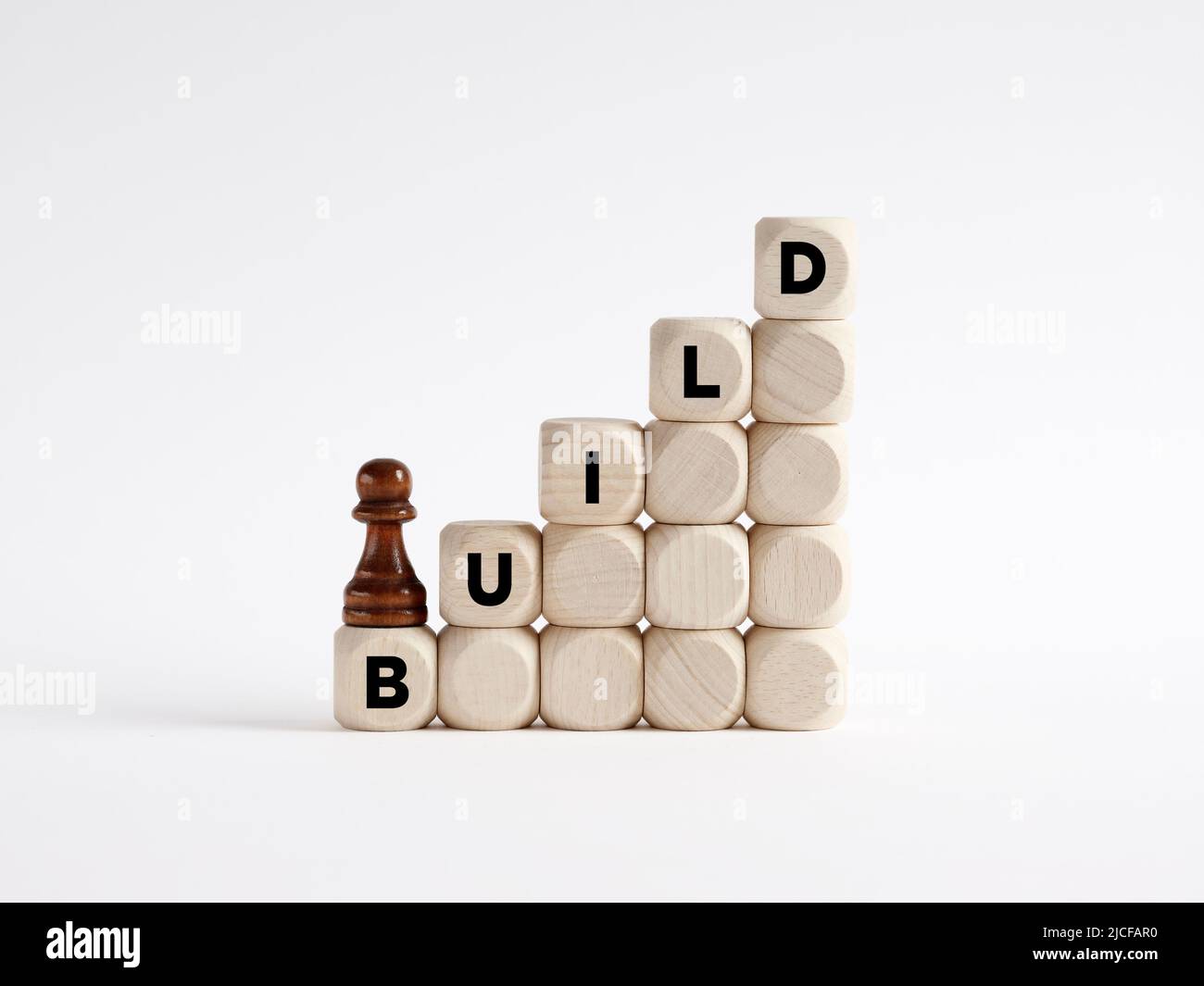 Schritt für Schritt ein Konzept zu erstellen oder zu konstruieren. Chess Pawn klettert die Leiter aus Holzwürfeln mit dem Wort Build. Stockfoto
