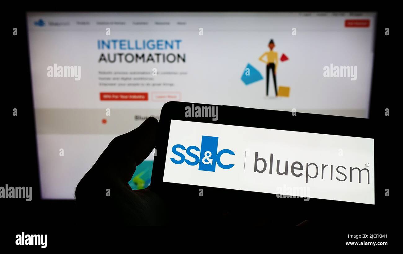 Person, die das Smartphone mit dem Logo des britischen Softwareunternehmens Blue Prism Limited auf dem Bildschirm vor der Website hält. Konzentrieren Sie sich auf die Telefonanzeige. Stockfoto