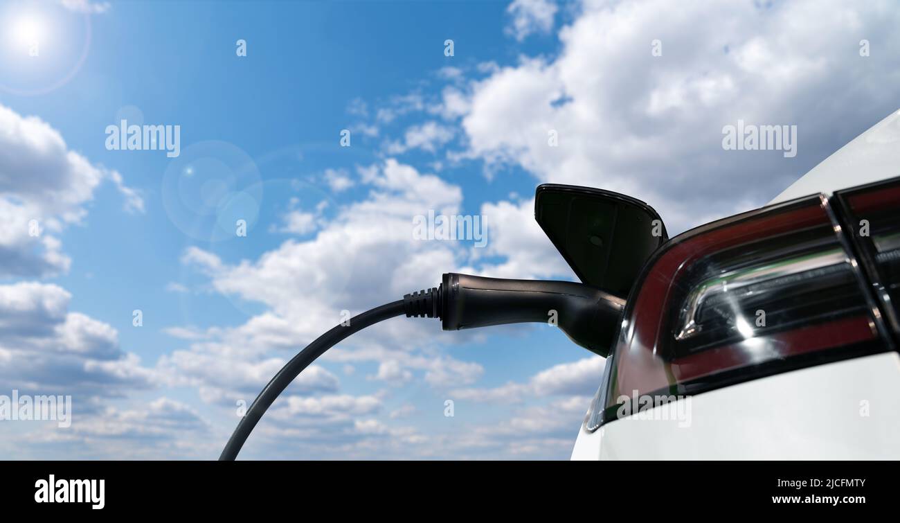 Nahaufnahme eines Elektroautos mit einer Ladestation auf einem Hintergrund des blauen Himmels Stockfoto