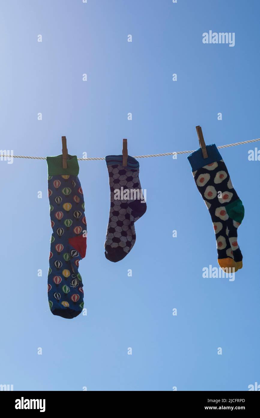 Einsame verschiedene Socken ohne Partner auf einer Wäscheleine, Symbolbild 'Lost Socks Memorial Day'. Stockfoto
