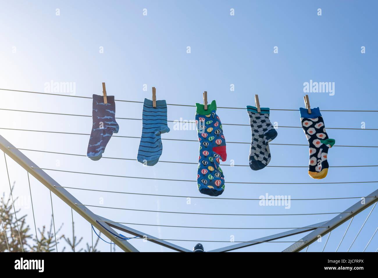 Einsame verschiedene Socken ohne Partner auf einer Wäscheleine, Symbolbild 'Lost Socks Memorial Day'. Stockfoto