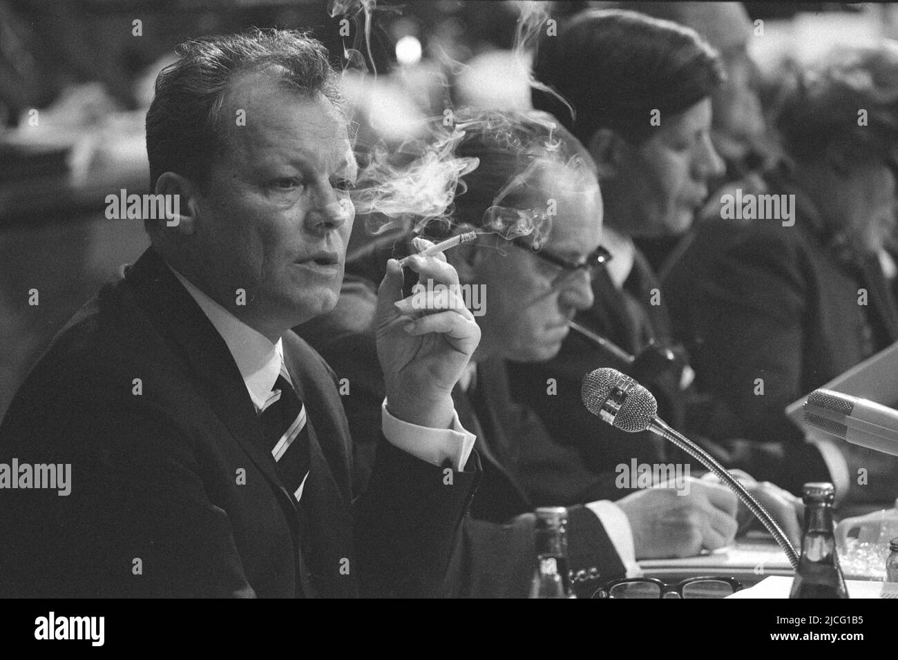 Nürnberg, Deutschland. 21.. Juli 2020. Willy BRANDT, SPD-Vorsitzender und Bundeskanzler, sitzt im Plenum und raucht eine Zigarette, hinter ihm Herbert WEHNER mit Pfeife und Helmut SCHMIDT, auf der SPD-Parteikonferenz 1968 in Nürnberg, 18. März 1968 Quelle: dpa/Alamy Live News Stockfoto