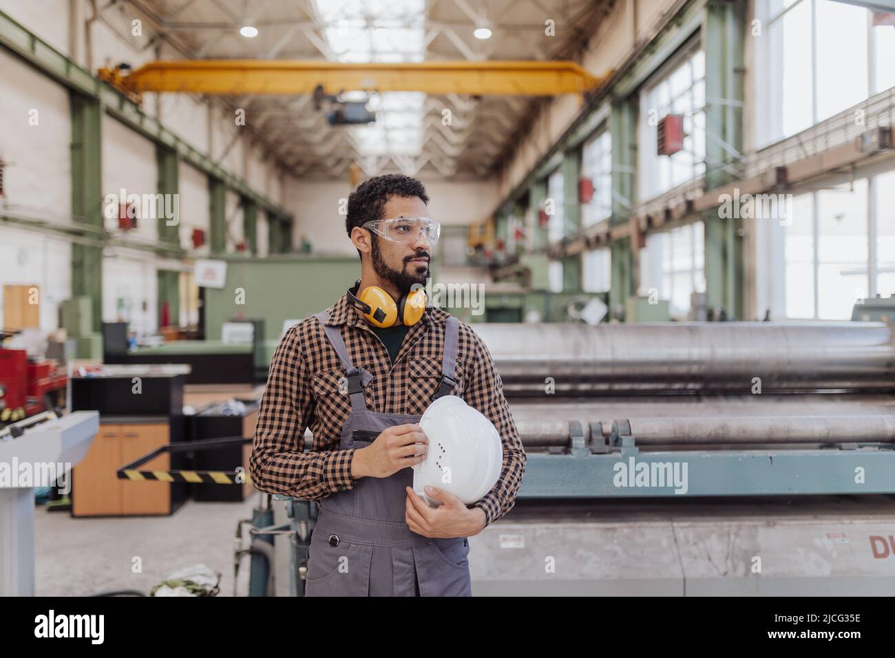 Arbeiter in der Schwerindustrie mit Sicherheitskopfhörern und Schutzhelm in der Industriefabrik Stockfoto