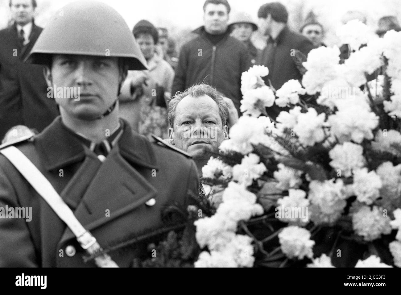 Bundeskanzler Willy BRANDT schaut bei der Kranzniederlegung im ehemaligen KZ Buchenwald anlässlich eines Treffens mit dem DDR-Ministerpräsidenten Willi Stoph am 19. März 1970 in Erfurt zwischen einem NVA-Soldaten und einem Blumenstrauß durch; schwarz-weiß-Schuss; Stockfoto