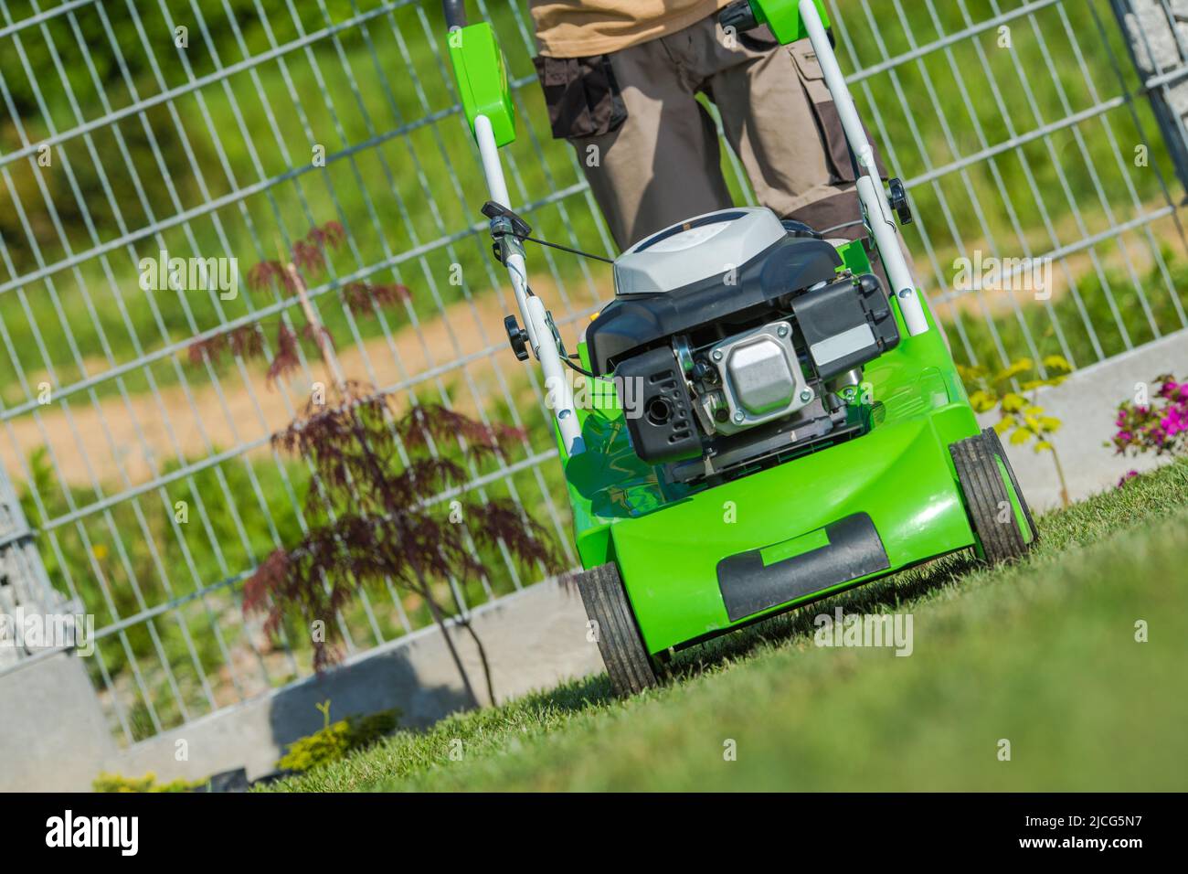 Nahaufnahme einer Rasenmäher-Outdoor-Ausrüstung, die von einem professionellen Grasschneider-Mann geschoben und betrieben wird, der regelmäßige Saisonarbeit leistet, um das Gesetz zu erhalten Stockfoto