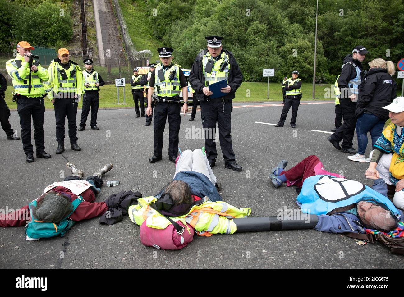 Coulport, Argyll, Schottland 13. Juni 2022 fünf ehemalige Greenham-Frauen und drei Mitglieder von Peace Pirates, einem Ableger von Trident Plowshares, führen eine Blockade im nuklearen Sprengkopflager von Coulport durch. Die ‘Greenham goss gefälschtes Blut auf sich selbst und inszenierten einen Einfall vor den Toren, der eine Seite des Eingangs in die Basis blockierte, während die Mitglieder von ‘Peace Pirates’ (pensionierter Lehrer Brian Quail, 84, mit einer Herztransplantation und durch einen kürzlichen Schlaganfall behindert, Willemien Hoogendorf aus Holland und Gillean Lawrence, eine Großmutter und Unterstützer von XR Peace) sperrten den Kreisverkehr weiter ein Stockfoto