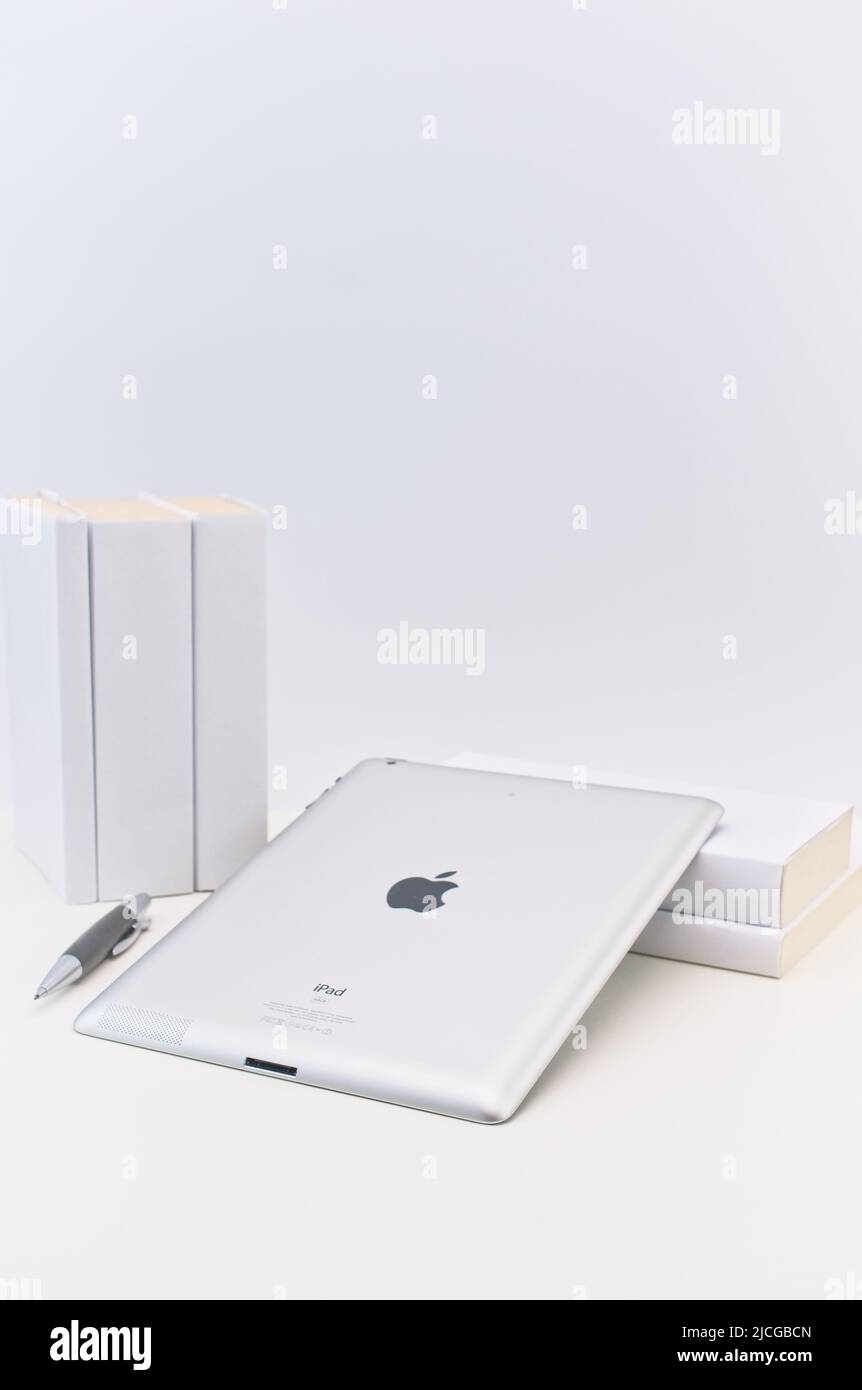 Apple ipad der ersten Generation auf einem hellen Schreibtisch mit Büchern an einer weißen Wand Stockfoto