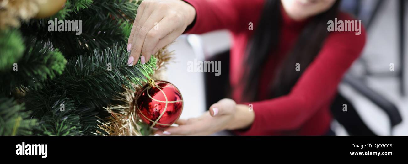 Frau im Rollstuhl schmückt weihnachtsbaum mit roter Kugel Stockfoto