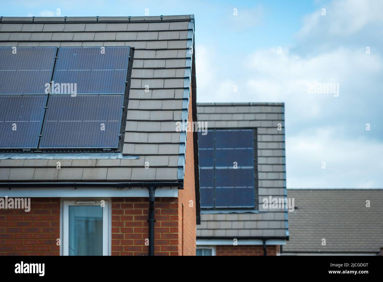 Solarmodule, die auf dem Dach eines modernen Neubaus in England montiert sind Stockfoto