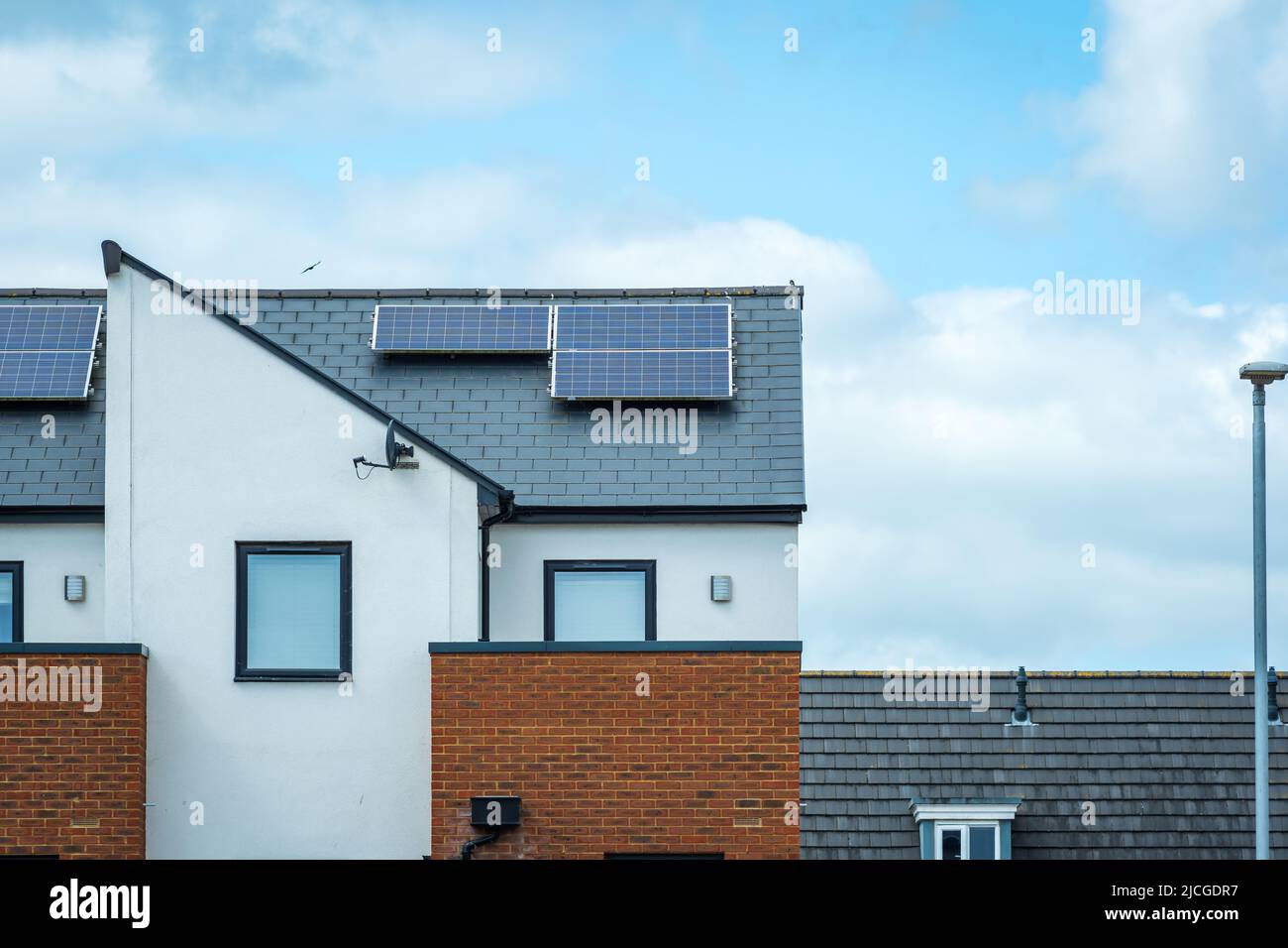 Solarmodule, die auf dem Dach eines modernen Neubaus in England montiert sind Stockfoto