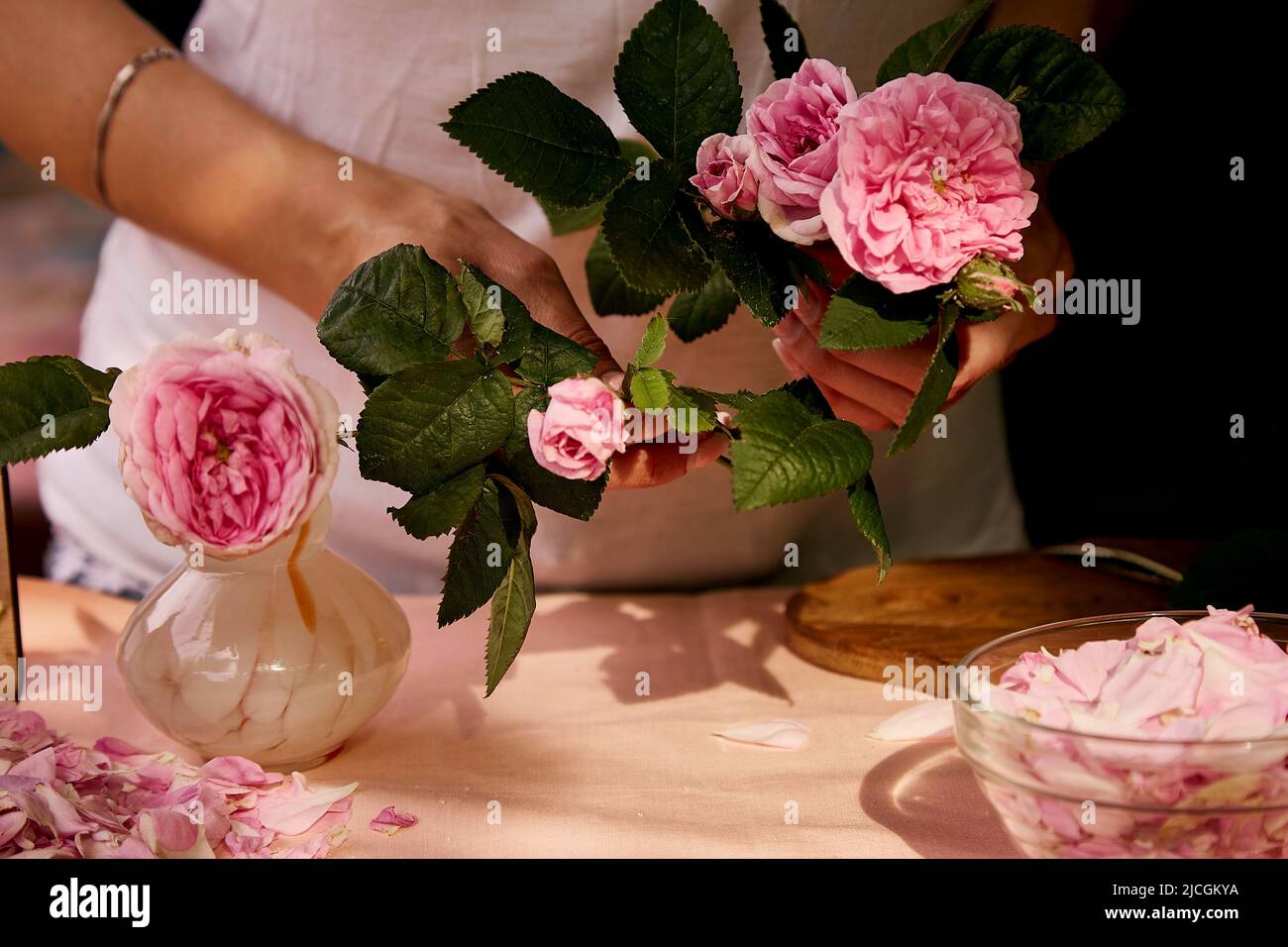 Frau bereitet Teerosenblüten zu. Ästhetische hausgemachte natürliche Tee-Rosenmarmelade mit Zucker, Zitrone und Tee Rosenblüten vorbereiten. Gesundes Rezept. Lifestyle p Stockfoto