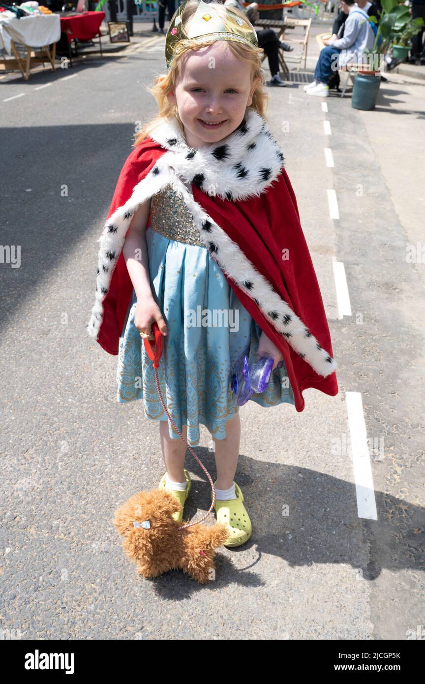 London, Hackney. Wilton Way Jubilee Street Party. Junges Mädchen mit einer Krone und einem roten Umhang und einem Spielzeug-Hund Stockfoto