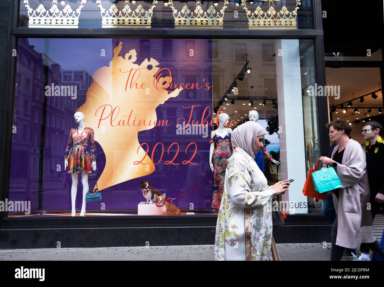 Central London, Regent Street. Shopper laufen vorbei an Guess-Bekleidungsgeschäft, das für das Jubiläum dekoriert ist Stockfoto