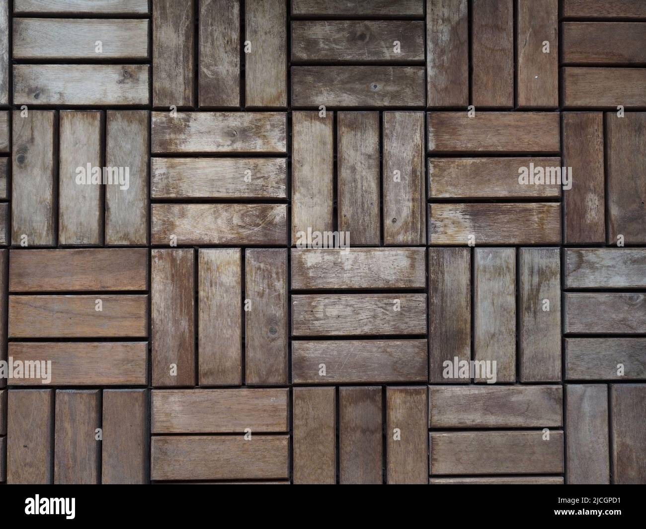 Verwitterte und verblasste Balkonterrasse aus nächster Nähe. Geometrische Parkettböden für den Außenbereich. Stockfoto