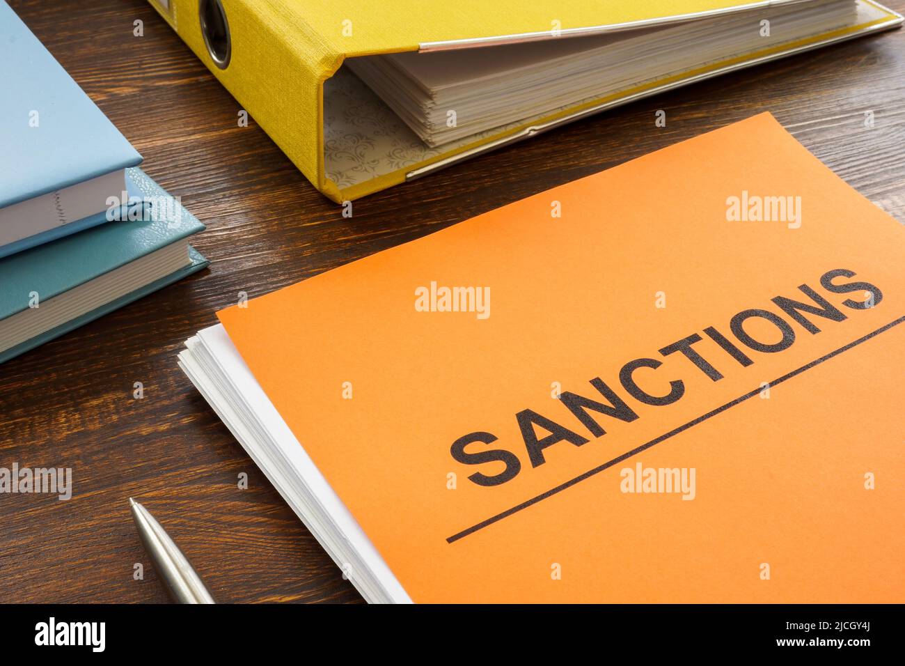 Ein Stapel Papiere über Sanktionen und ein Ordner in der Nähe. Stockfoto