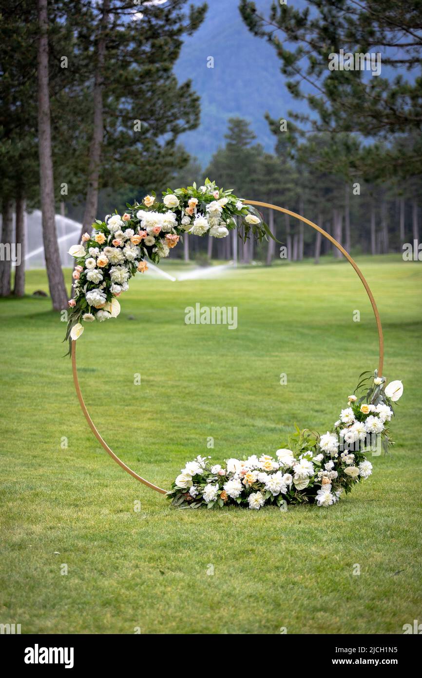 Hochzeitsbogen mit frischen Blumen auf einem grünen Rasen für eine Hochzeitszeremonie angeordnet Stockfoto