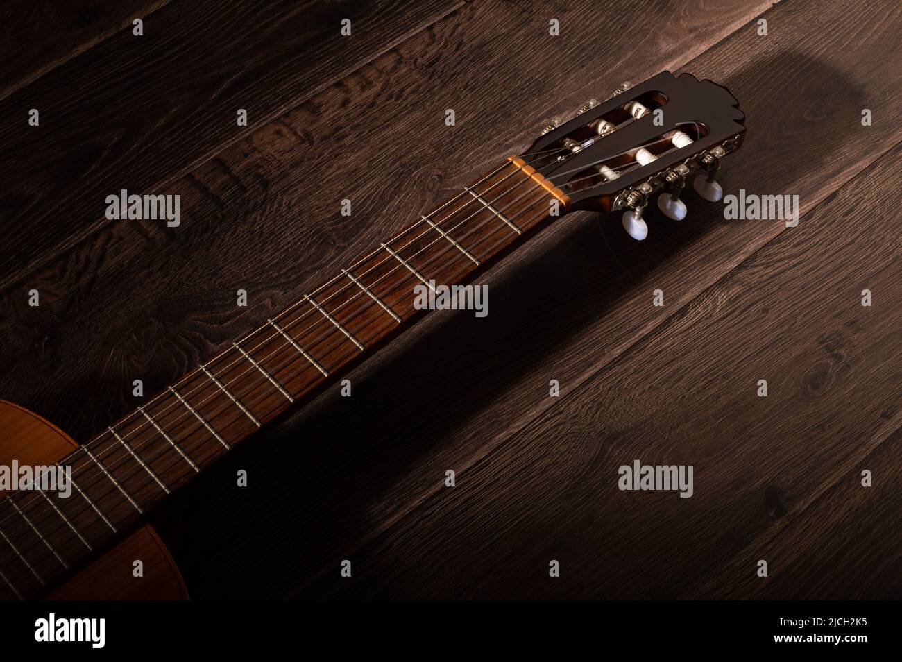 Klassische Gitarre Griffbrett und Maschinenkopf auf einem dunklen Holzhintergrund mit Kopierraum Stockfoto