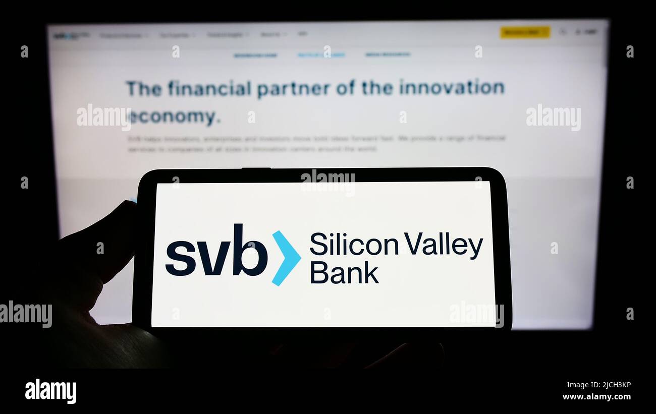Person, die das Smartphone mit dem Logo des US-Finanzunternehmens Silicon Valley Bank (SVB) auf dem Bildschirm vor der Website hält. Konzentrieren Sie sich auf die Telefonanzeige. Stockfoto