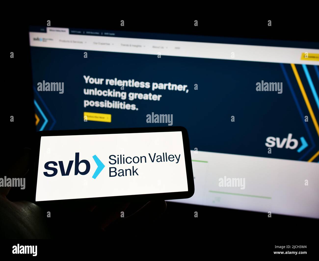 Person mit Mobiltelefon und Logo des US-Finanzunternehmens Silicon Valley Bank (SVB) auf dem Bildschirm vor der Webseite. Konzentrieren Sie sich auf die Telefonanzeige. Stockfoto