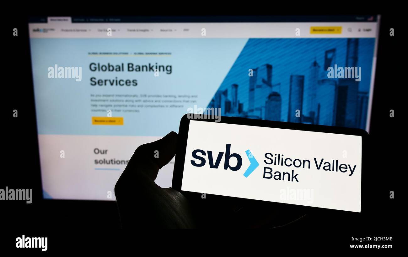 Person mit Mobiltelefon und Logo der amerikanischen Silicon Valley Bank (SVB) auf dem Bildschirm vor der Webseite. Konzentrieren Sie sich auf die Telefonanzeige. Stockfoto