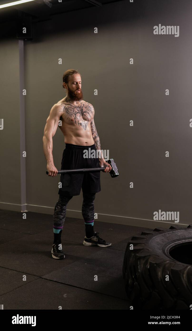 Reifen Schlitten Hammer muskulöses Rad Mann schlagen Übung Workout Kraft, Konzept Ausrüstung stark von sportlich aus Sportswear Konzentration, männlich Stockfoto