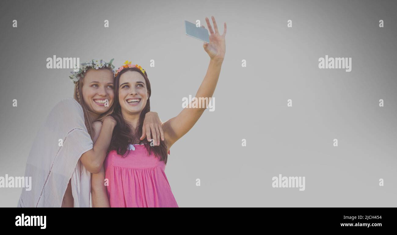 Zwei kaukasische Frauen, die ein Selfie vom Smartphone gegen den Kopierplatz auf grauem Hintergrund machen Stockfoto