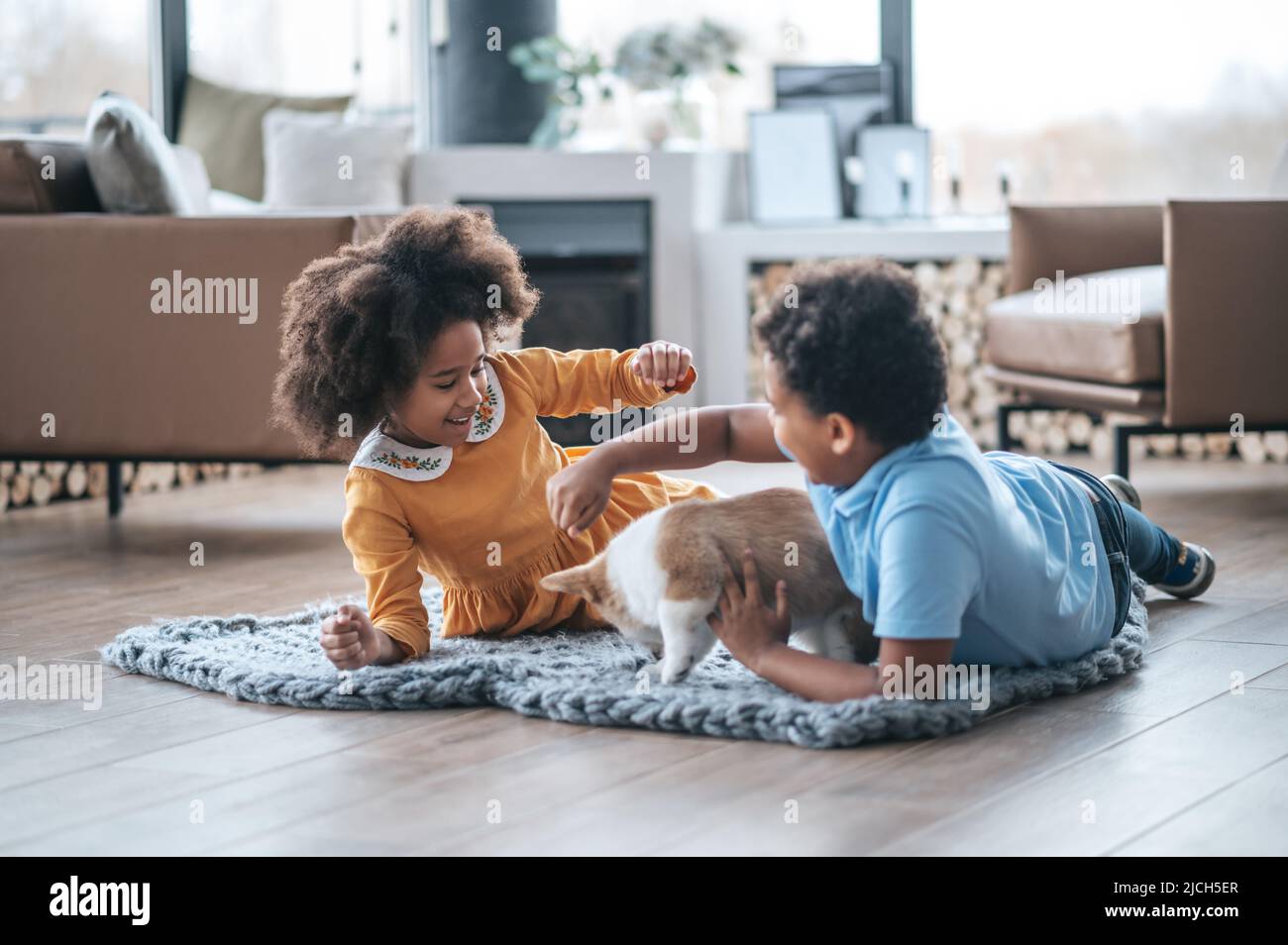 Zwei lockige Kinder, die mit dem Welpen spielen Stockfoto
