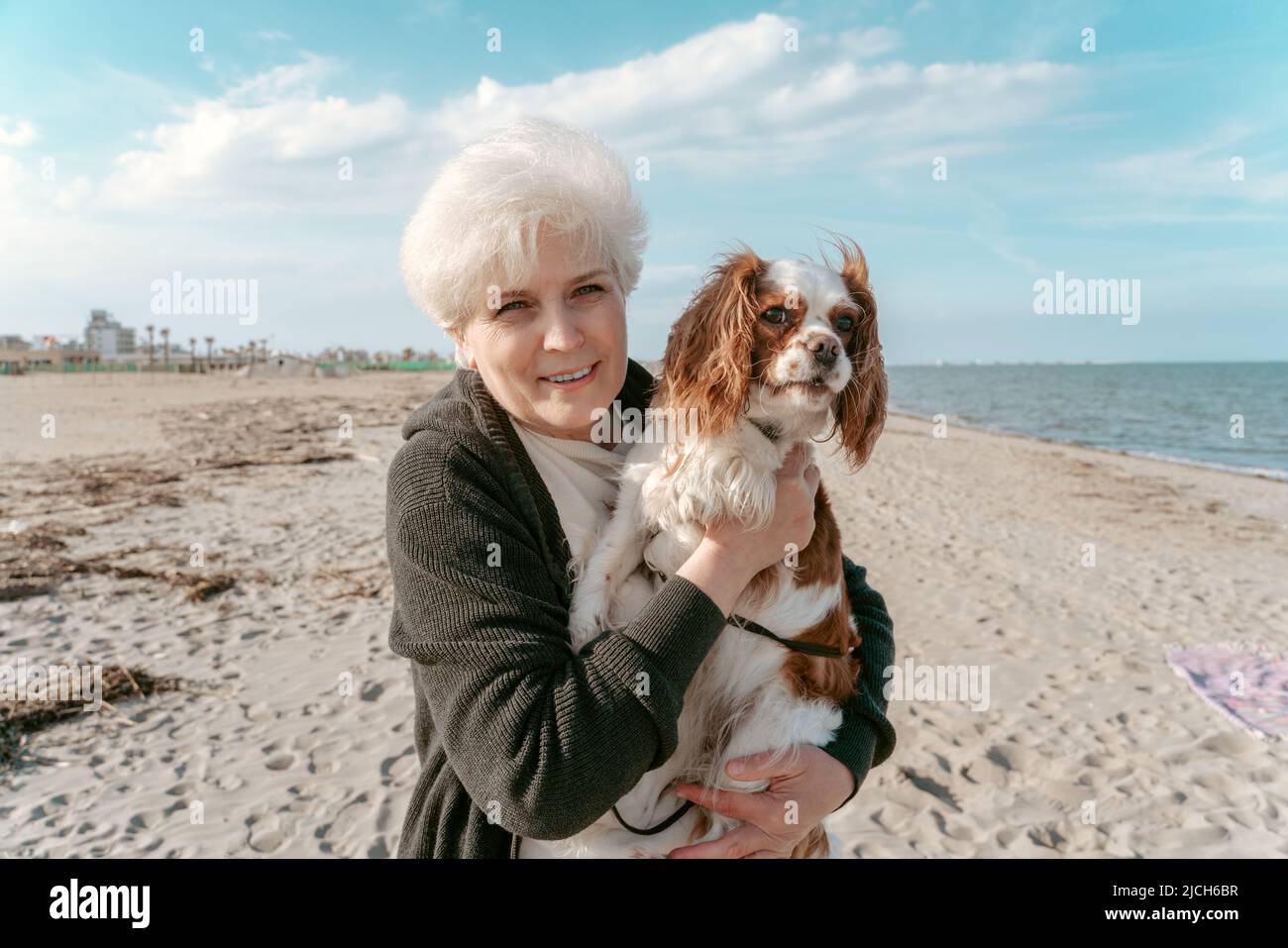 Fröhliche ältere Dame mit ihrem Haustier am Meer Stockfoto
