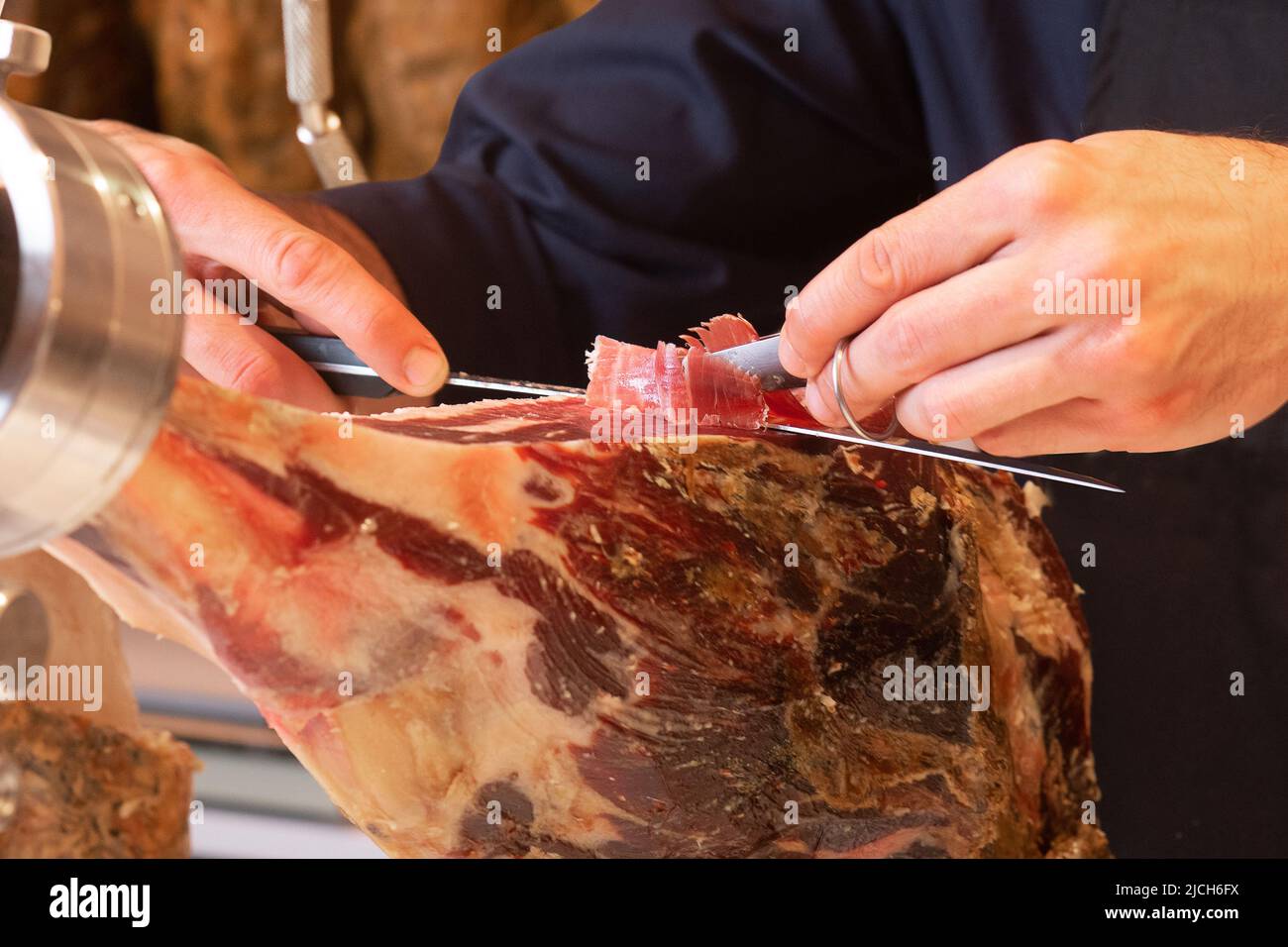 Im Vordergrund schneidet der Metzger Span spanischen serrano-Schinken Stockfoto