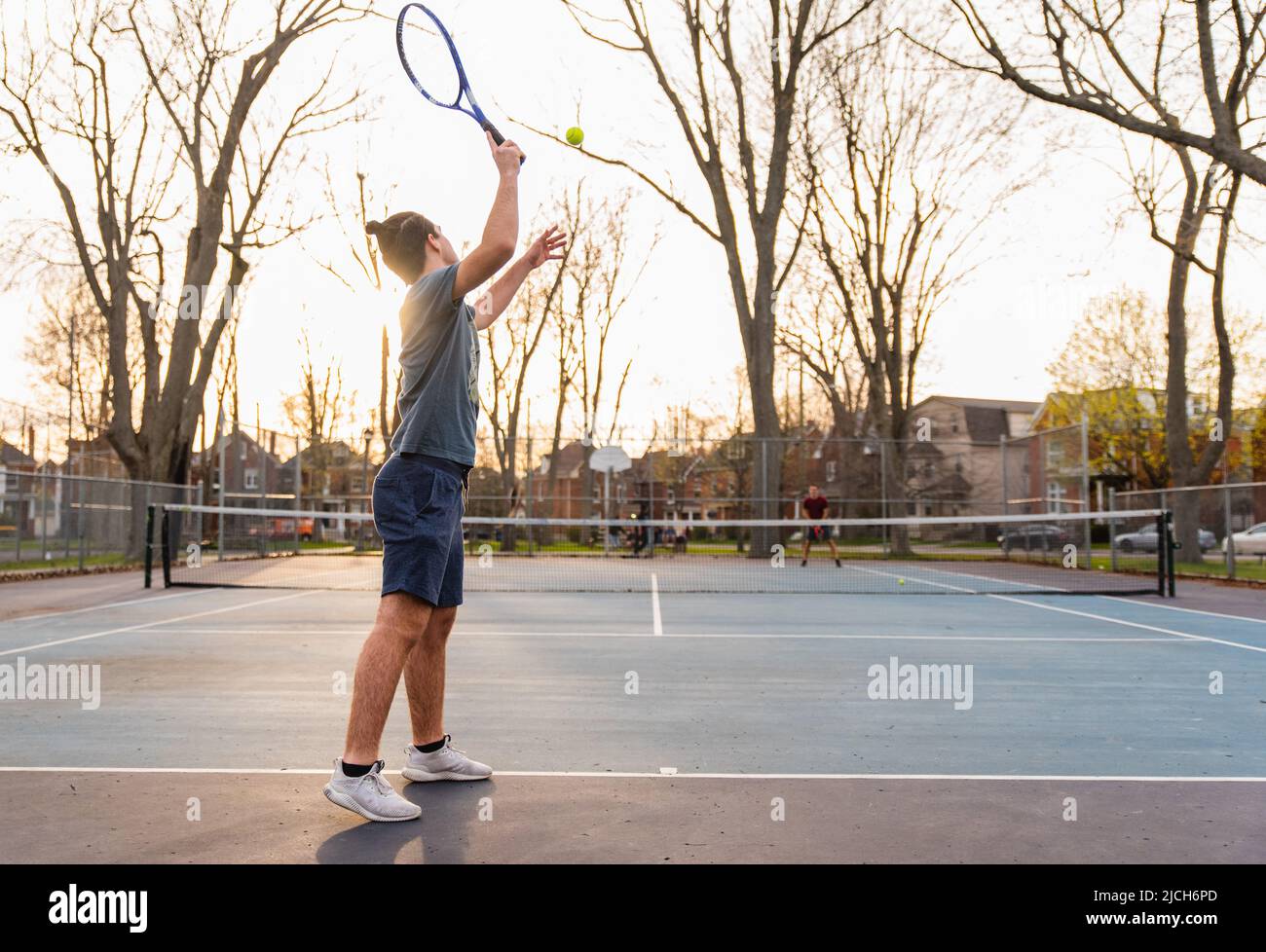 Teenager, der im Frühjahr auf dem Hartplatz im Freien Tennis spielt. Stockfoto