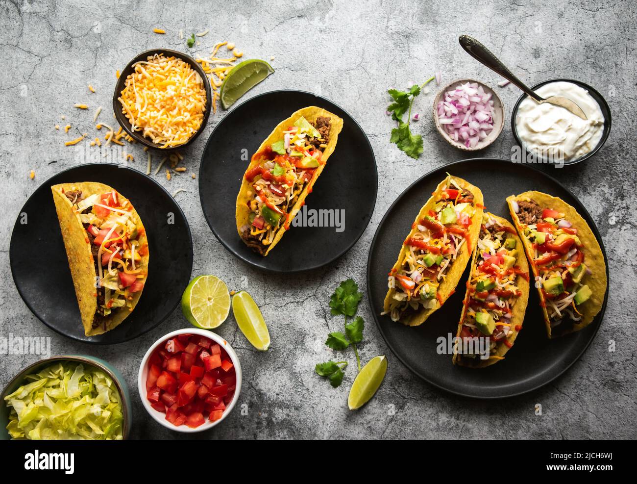 Tacos aus Hartschalen auf Tellern mit Rindfleisch, Salat, Tomaten, Käse. Stockfoto